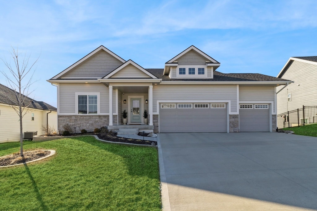 craftsman house with a garage, central AC, and a front lawn