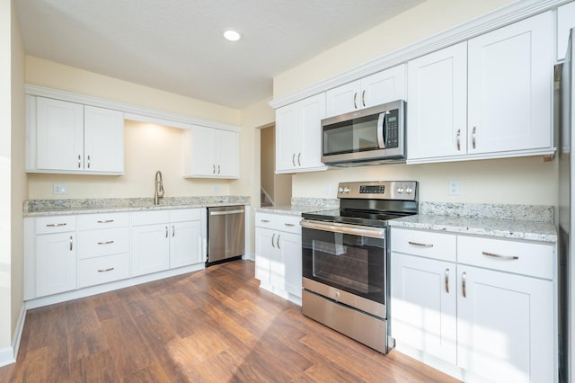 kitchen featuring stainless steel appliances, white cabinetry, dark hardwood / wood-style floors, and sink