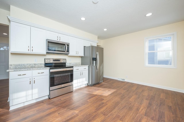 kitchen featuring dark hardwood / wood-style flooring, light stone countertops, stainless steel appliances, and white cabinets