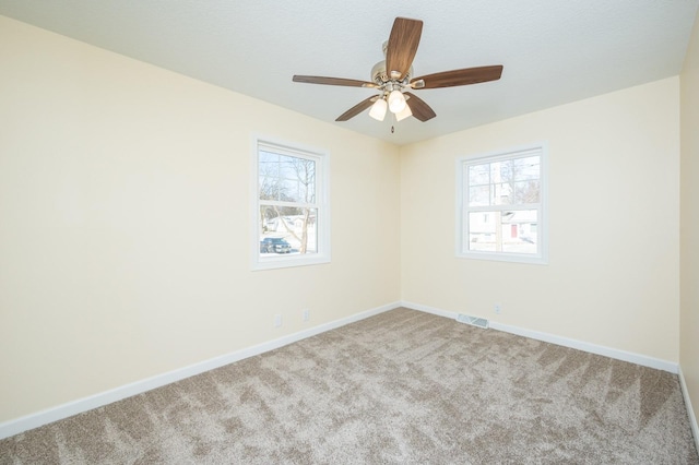 unfurnished room with a wealth of natural light, light colored carpet, and ceiling fan