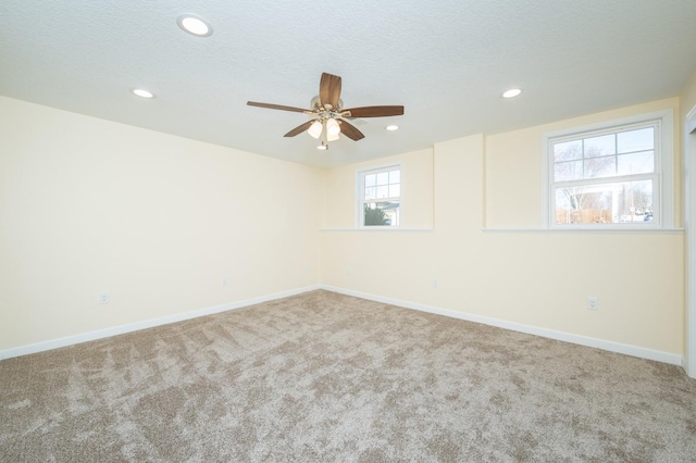 carpeted spare room featuring ceiling fan, plenty of natural light, and a textured ceiling