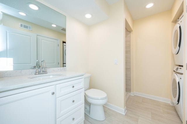 bathroom with stacked washer and clothes dryer, toilet, vanity, and a shower