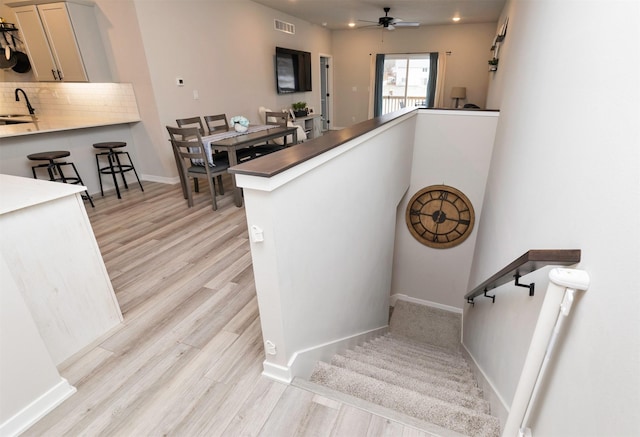 staircase with hardwood / wood-style flooring, ceiling fan, and sink