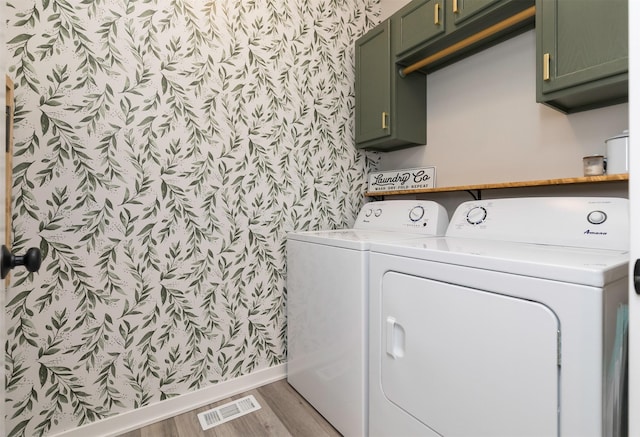 laundry room with washer and dryer, cabinets, and light wood-type flooring