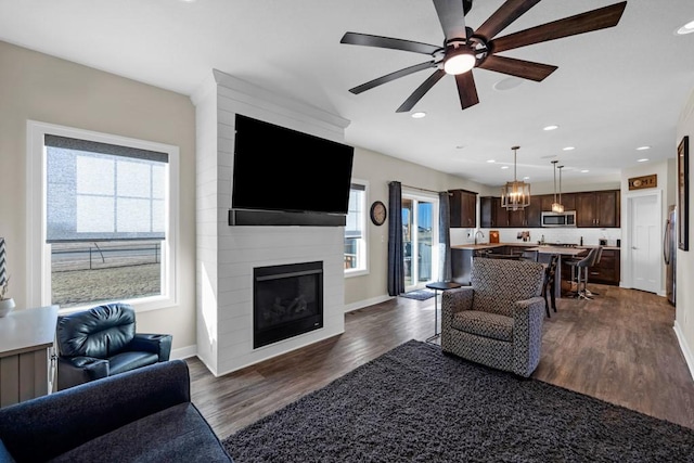 living room featuring a fireplace, a wealth of natural light, dark hardwood / wood-style floors, and ceiling fan