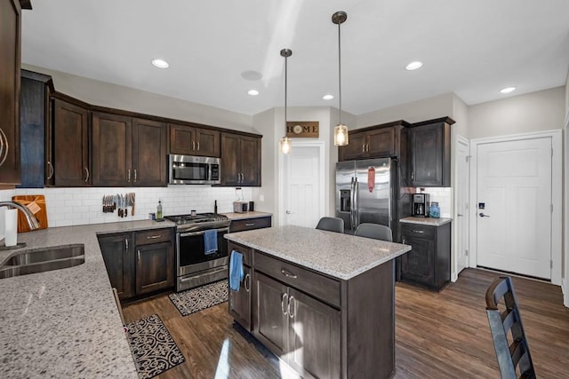 kitchen with tasteful backsplash, sink, hanging light fixtures, light stone counters, and stainless steel appliances