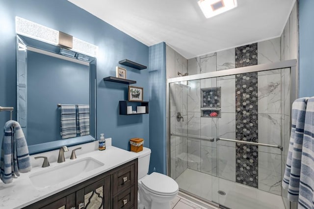 bathroom featuring toilet, vanity, and a shower with shower door