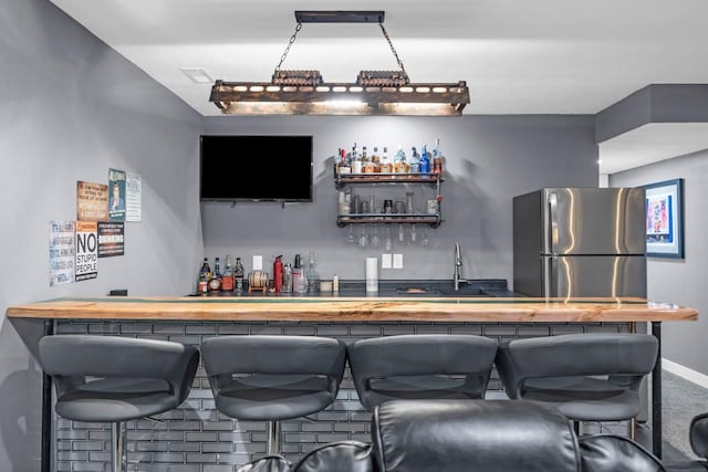 bar featuring sink and stainless steel fridge