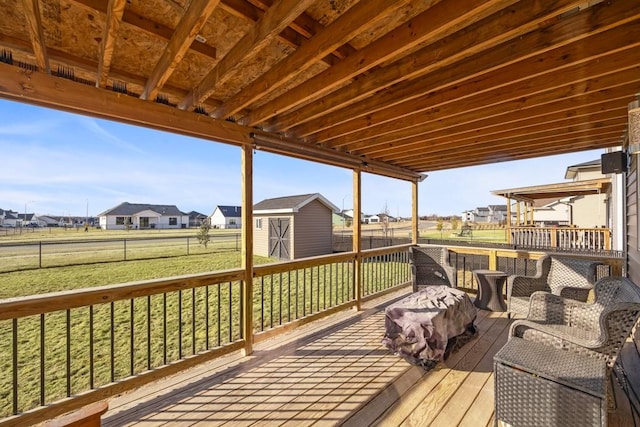 wooden terrace with a storage shed and a lawn