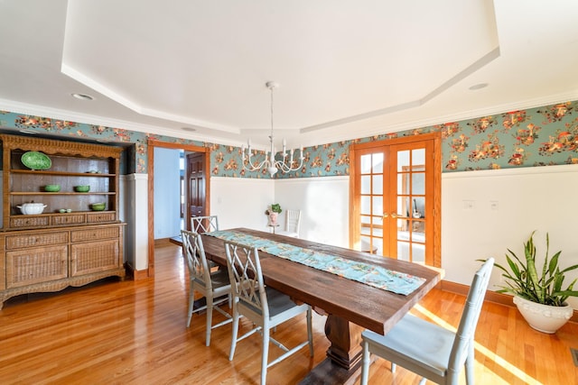 dining area featuring a raised ceiling, light wood-style flooring, and wallpapered walls