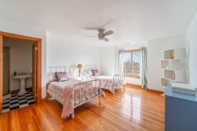 bedroom with baseboards, light wood-style flooring, a ceiling fan, and a textured ceiling