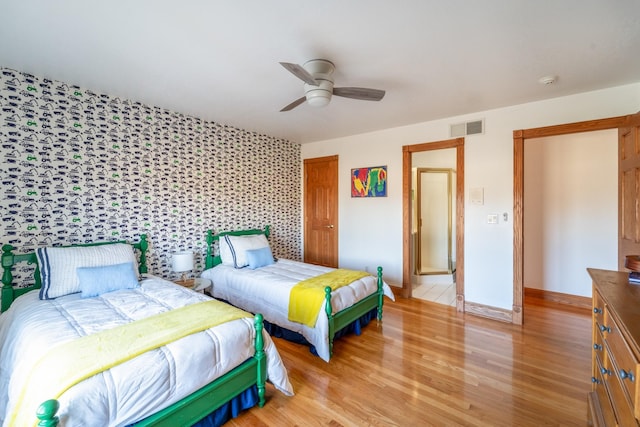 bedroom with visible vents, baseboards, a ceiling fan, light wood-style flooring, and an accent wall