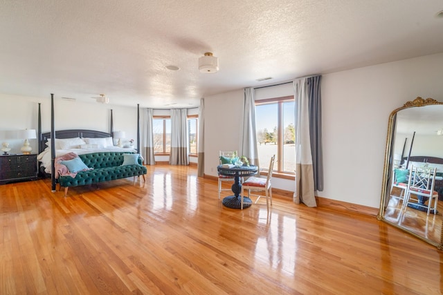 bedroom with light wood-type flooring, a textured ceiling, and baseboards