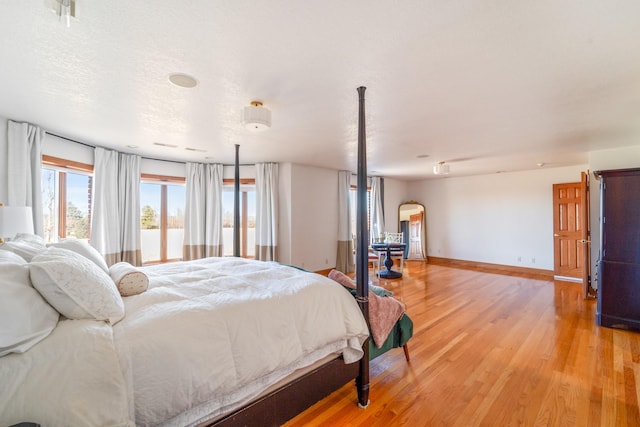 bedroom featuring a textured ceiling, light wood finished floors, and baseboards