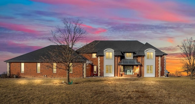 view of front of home featuring brick siding and a yard