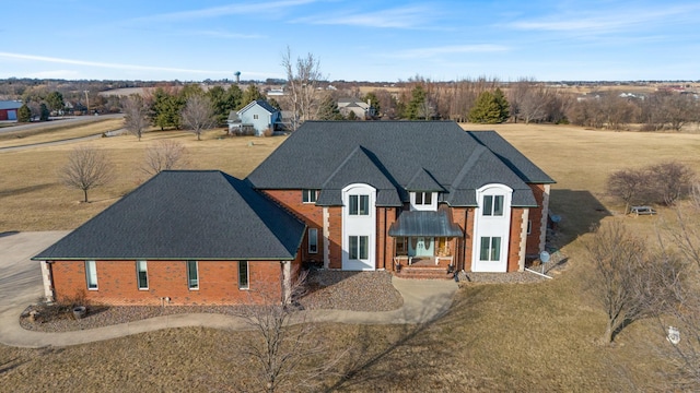 view of front of house with brick siding and roof with shingles