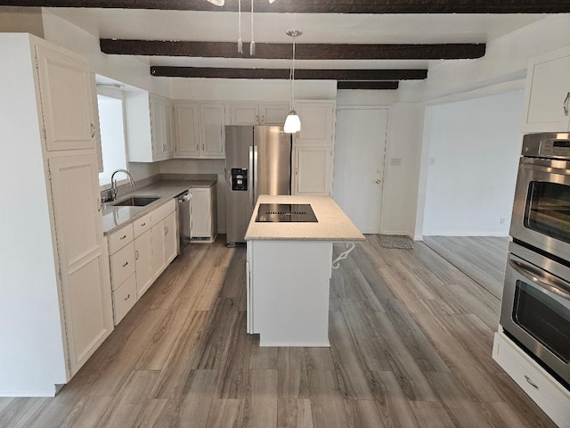 kitchen featuring sink, beam ceiling, decorative light fixtures, and a kitchen island