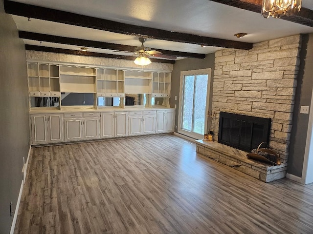 unfurnished living room with beam ceiling, a fireplace, light hardwood / wood-style floors, and ceiling fan