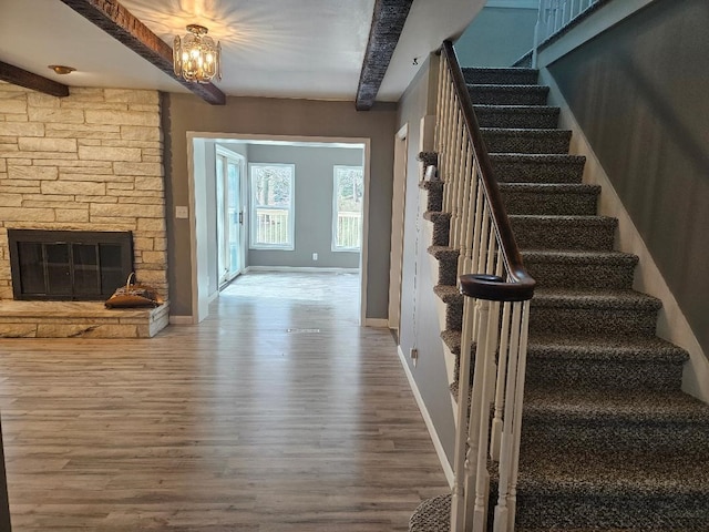 interior space featuring beam ceiling, hardwood / wood-style flooring, a fireplace, and a chandelier