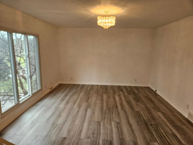 spare room featuring hardwood / wood-style flooring and a notable chandelier