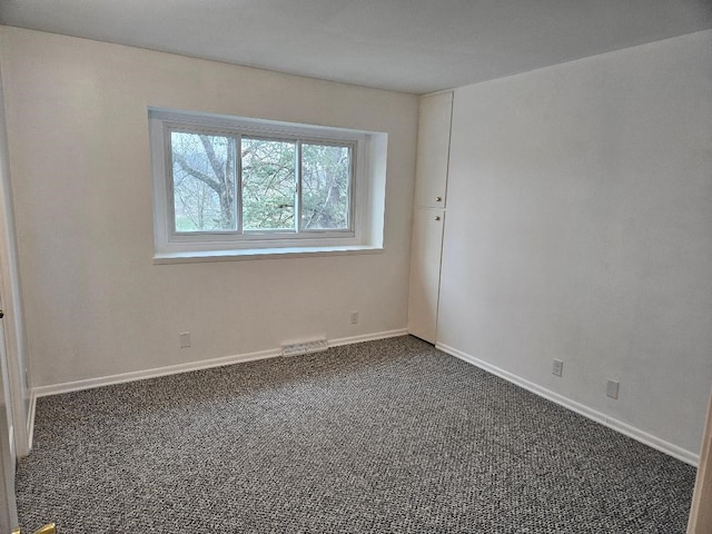 spare room with dark carpet