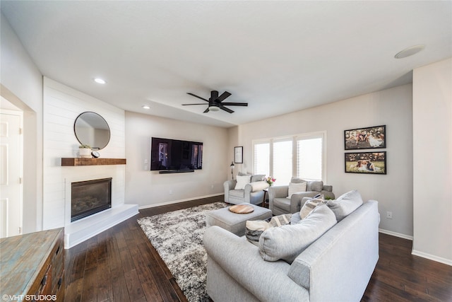 living room with dark wood-type flooring, ceiling fan, and a fireplace