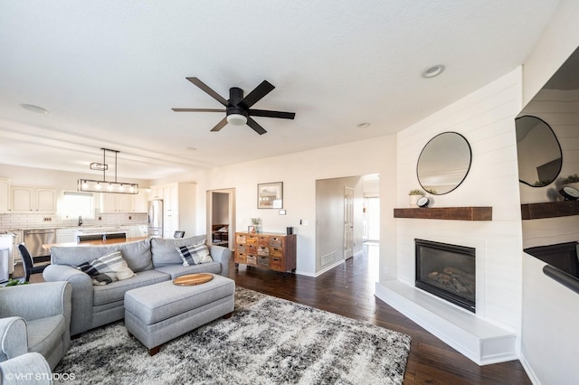 living room featuring a fireplace, dark wood-type flooring, and ceiling fan