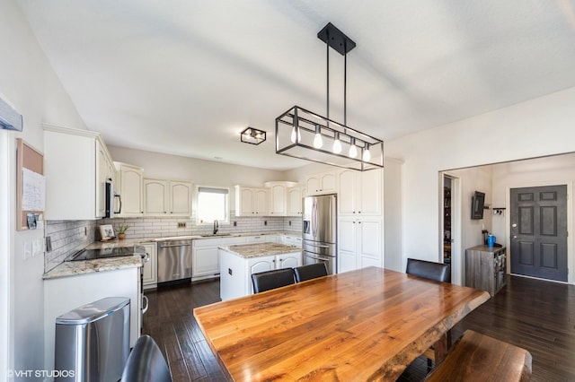 kitchen featuring sink, tasteful backsplash, a center island, stainless steel appliances, and light stone countertops