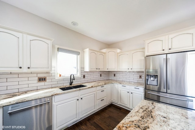 kitchen with sink, white cabinetry, appliances with stainless steel finishes, light stone countertops, and decorative backsplash