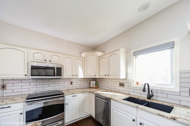 kitchen with light stone countertops, appliances with stainless steel finishes, sink, and backsplash