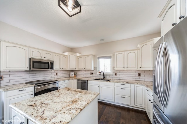 kitchen with a kitchen island, appliances with stainless steel finishes, sink, decorative backsplash, and light stone counters