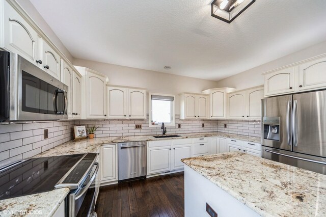 kitchen featuring appliances with stainless steel finishes, dark hardwood / wood-style floors, sink, backsplash, and light stone countertops