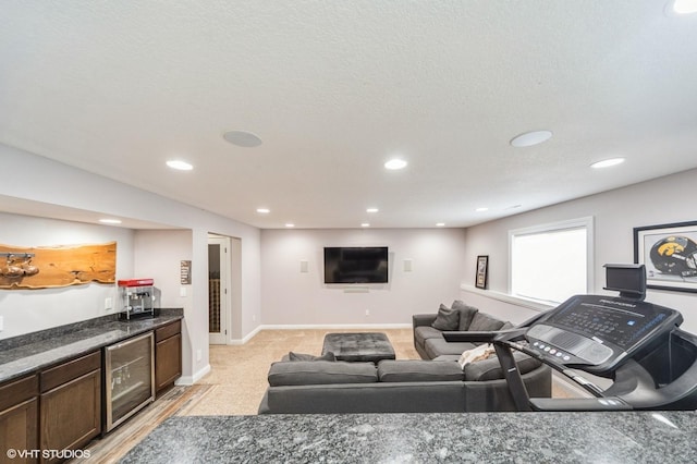 living room featuring wine cooler, bar area, and a textured ceiling