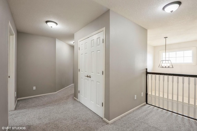 hallway featuring carpet flooring, baseboards, and a textured ceiling