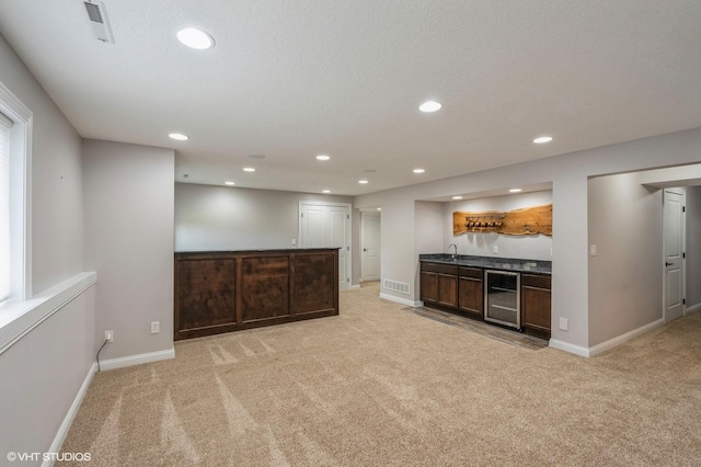kitchen with baseboards, light carpet, a sink, and visible vents