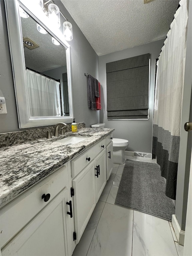 bathroom with vanity, a textured ceiling, and toilet