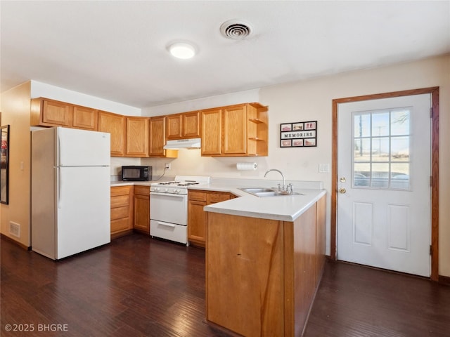 kitchen featuring sink, dark wood-type flooring, white appliances, and kitchen peninsula