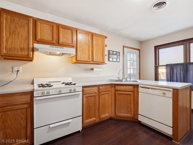 kitchen featuring dark hardwood / wood-style flooring, sink, white appliances, and kitchen peninsula