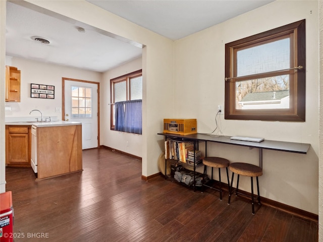 kitchen with dishwasher, sink, a breakfast bar area, dark hardwood / wood-style flooring, and kitchen peninsula