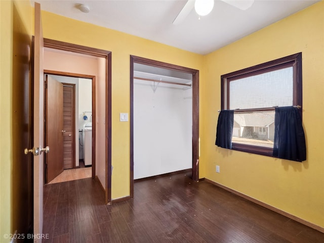 unfurnished bedroom with washer / dryer, dark hardwood / wood-style floors, ceiling fan, and a closet