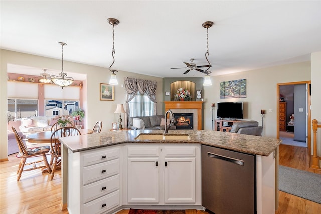 kitchen with pendant lighting, sink, white cabinetry, an island with sink, and stainless steel dishwasher