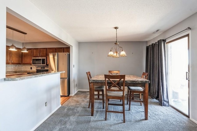 dining area featuring a chandelier, light carpet, a textured ceiling, and baseboards