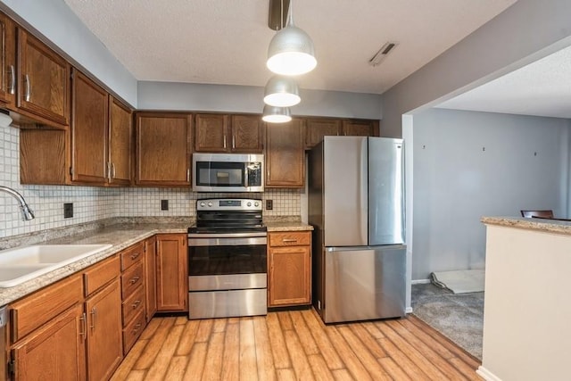 kitchen featuring tasteful backsplash, visible vents, appliances with stainless steel finishes, light wood-style floors, and a sink