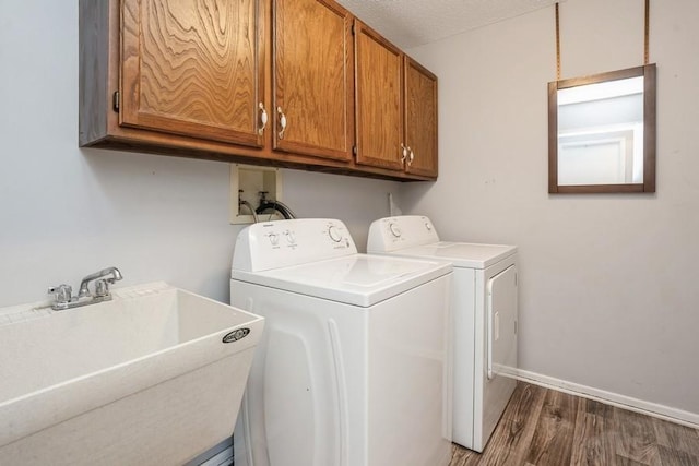 laundry area featuring dark wood-style flooring, cabinet space, a sink, independent washer and dryer, and baseboards