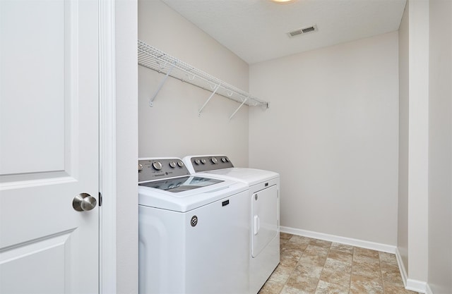 laundry room featuring washing machine and clothes dryer, visible vents, baseboards, laundry area, and a textured ceiling