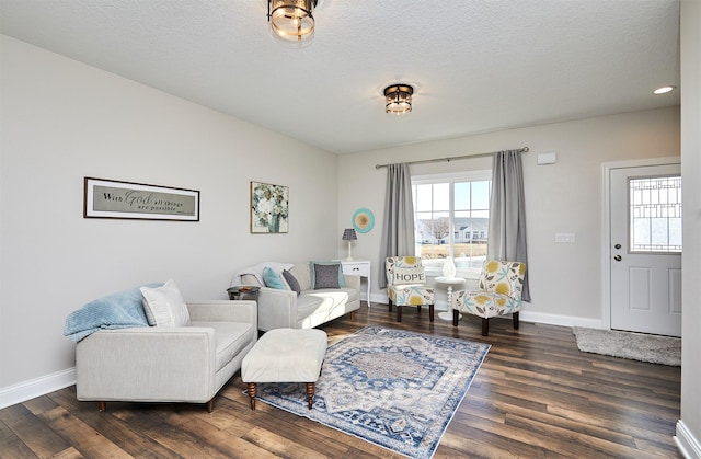 living room featuring baseboards, a textured ceiling, and wood finished floors