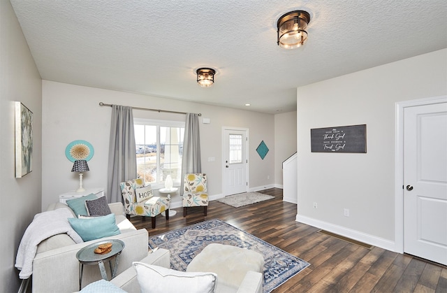 living room with dark wood finished floors, a textured ceiling, and baseboards