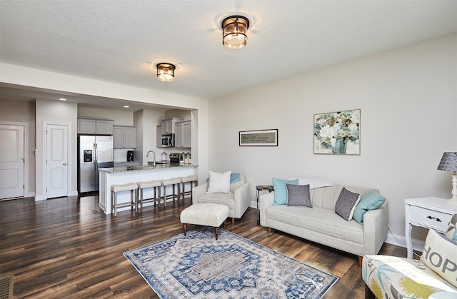 living room with baseboards, dark wood-type flooring, and a textured ceiling