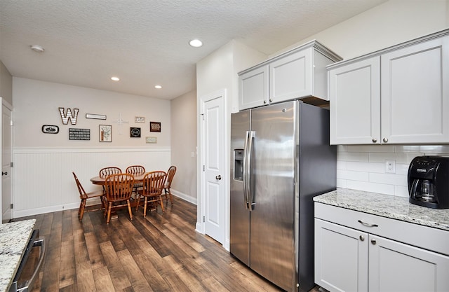 kitchen with light stone counters, dark wood finished floors, stainless steel fridge with ice dispenser, a textured ceiling, and tasteful backsplash