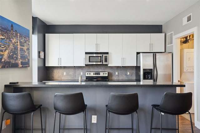 kitchen featuring white cabinetry, decorative backsplash, a breakfast bar area, and stainless steel appliances